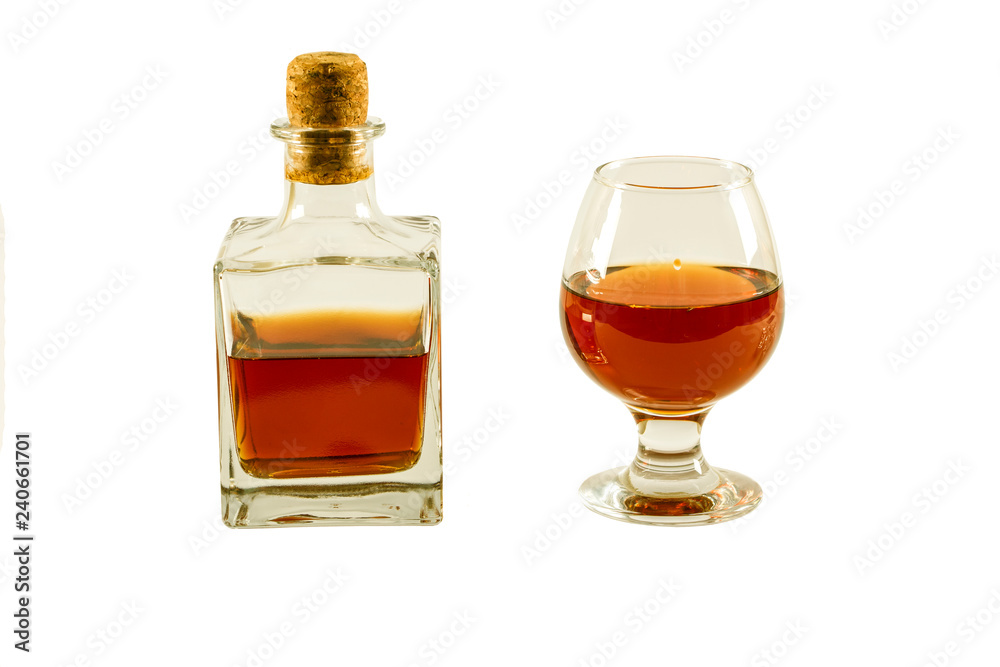 A glass of whiskey with ice or brandy and a square carafe isolated on a white background. Whiskey with ice in a glass against white background. A glass of whiskey with ice or brandy and a square carafe isolated on a white background. Whiskey with ice in a glass against white background.