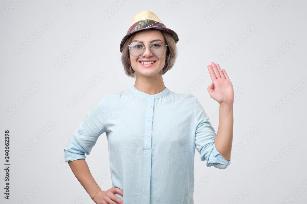 Friendly-looking european teenager dressed in blue shirt saying hello, waving her hand. Positive human emotions, feelings or facial expressions Friendly-looking european teenager dressed in blue shirt saying hello, waving her hand. Positive human emotions, feelings or facial expressions