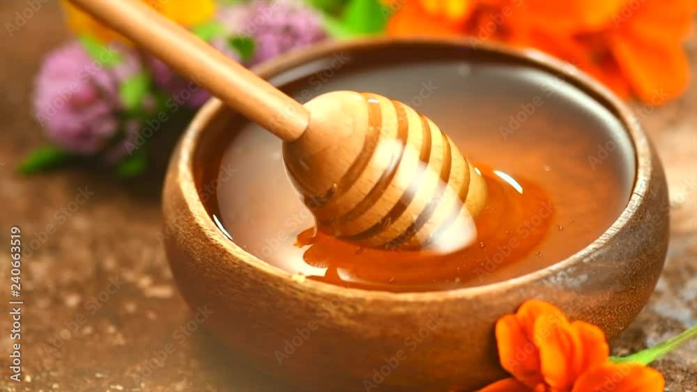 Honey pouring in wooden bowl. Honey closeup. Healthy organic thick honey dipping from the wooden honey spoon. Slow motion. 3840X2160 4K UHD video footage Honey pouring in wooden bowl. Honey closeup. Healthy organic thick honey dipping from the wooden honey spoon. Slow motion. 3840X2160 4K UHD video footage