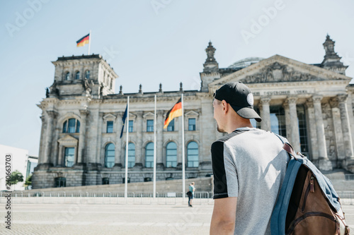 Photography A guy or a tourist with a backpack next to the Reichstag building in Berlin in Germany walks and watches the sights of the city