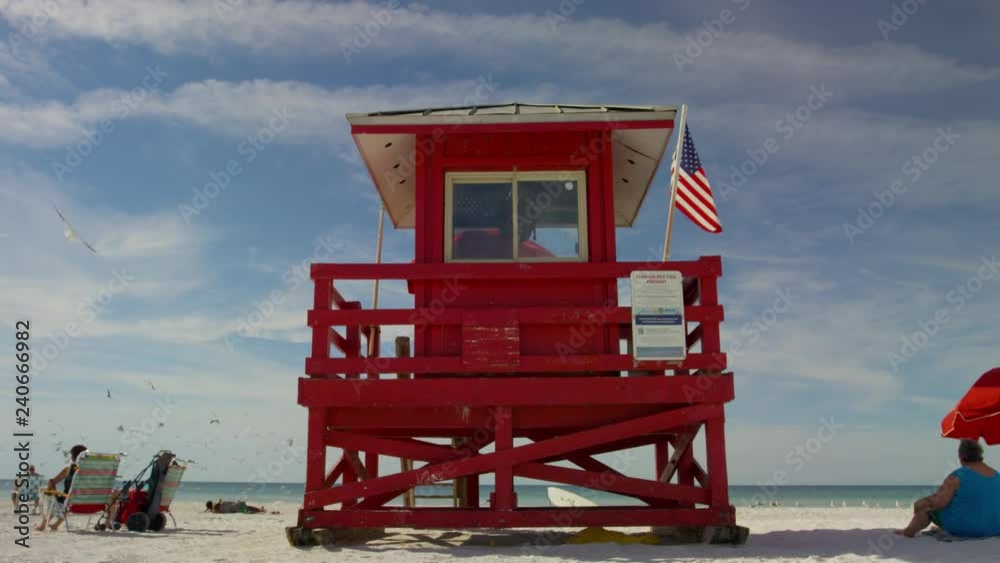 Lifeguard with american Flag florida beachFlorida Beach with people lifeguard houses umbrellas afternoon lighting american flag calm ocean A LIFEGUARD STATION WITH GREEN FLAG ON THE BEACH Lifeguard with american Flag florida beachFlorida Beach with people lifeguard houses umbrellas afternoon lighting american flag calm ocean A LIFEGUARD STATION WITH GREEN FLAG ON THE BEACH