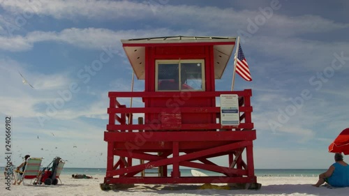 Lifeguard with american Flag florida beachFlorida Beach with people lifeguard houses umbrellas afternoon lighting american flag calm ocean A LIFEGUARD STATION WITH GREEN FLAG ON THE BEACH photo