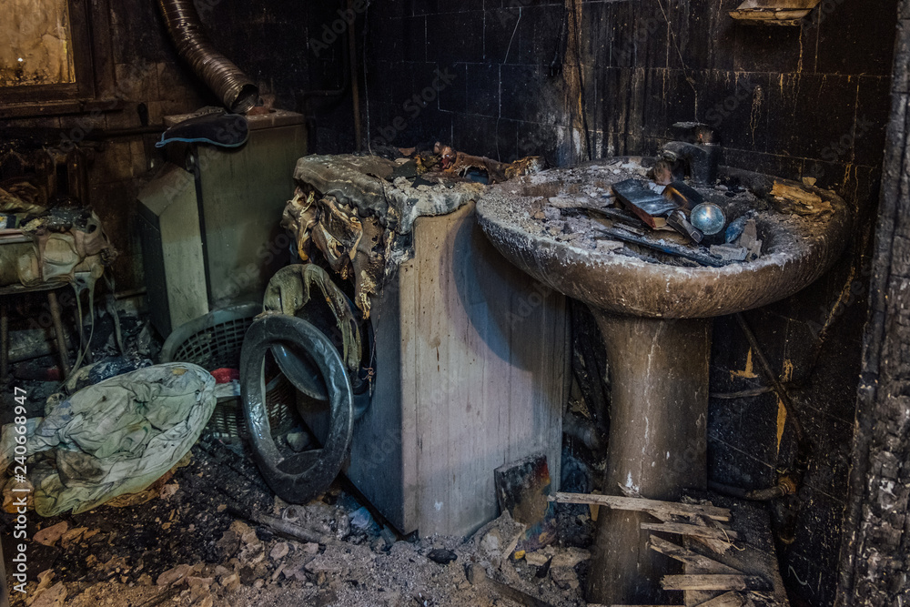 Burnt house interior. Burned burnt bathroom, Fused remains of furniture and washing machine