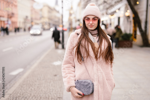 Fashion woman walking on the city street, wear pantone color jaket with pink glasses and look to camera. Copy space. - Image © Serhiy Hipskyy
