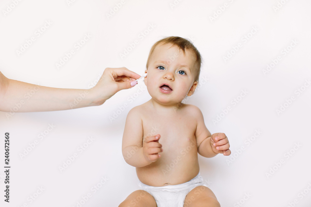 closeup Portrait baby. Mother cleaning her baby ears with cotton swab, isolated on white background. Newborn hygiene. concept cleaning wipe, pure, clean. closeup Portrait baby. Mother cleaning her baby ears with cotton swab, isolated on white background. Newborn hygiene. concept cleaning wipe, pure, clean.