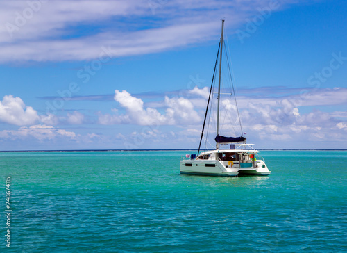 Lonely catamaran in a beautiful turquoise lagoon near the island Bora Bora in the Leeward group of the Society Islands of French Polynesia.