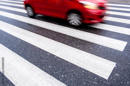 one red, fast, dangerous blurred car on the crosswalk, center top, no people, wet asphalt, empty space,