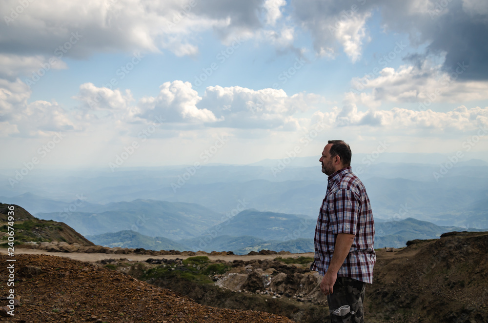 Man dressed for hiking is walking on top of Kopaonik mountain, Serbia and watching landscape