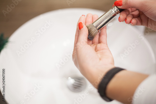 Makr up brush. Woman washing dirty makeup brush with soap and foam in the sink