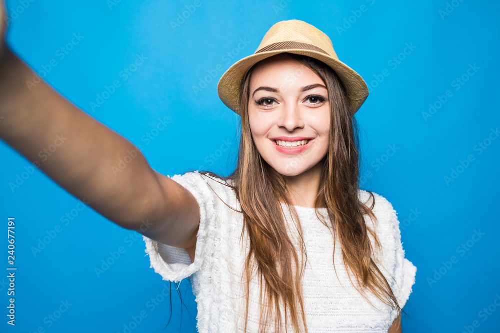 Portrait of a young woman taking a selfie isolated over blue background Portrait of a young woman taking a selfie isolated over blue background