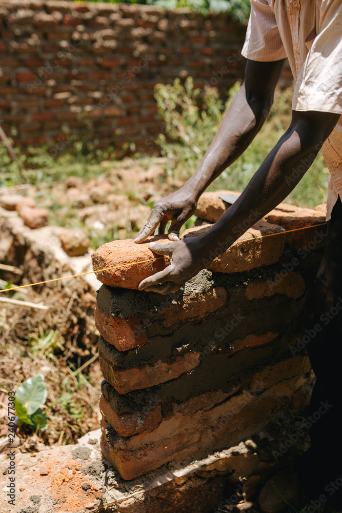 Fototapeta premium Man building a wall in Uganda, Africa