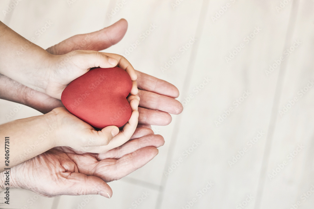 people, age, family, love and health care concept - close up of adult woman and child hands holding red heart over lights background. people, age, family, love and health care concept - close up of adult woman and child hands holding red heart over lights background.