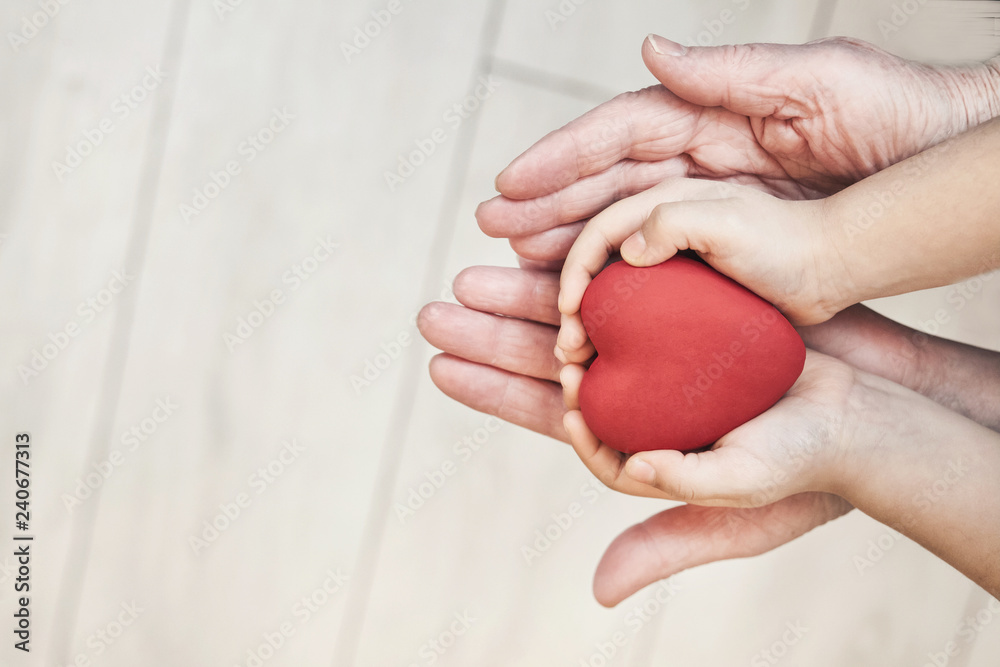 people, age, family, love and health care concept - close up of adult woman and child hands holding red heart over lights background. 