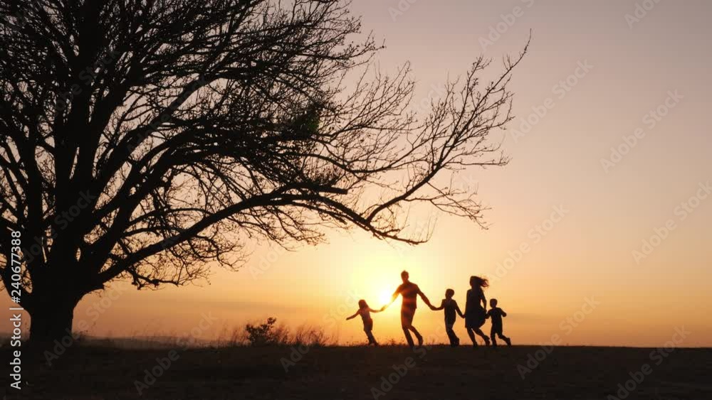 Silhouettes of family holding the hands and running in the meadow during sunset. Silhouettes of family holding the hands and running in the meadow during sunset.