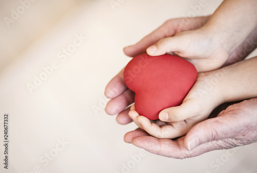 Fototapeta Naklejka Na Ścianę i Meble -  people, age, family, love and health care concept - close up of adult woman and child hands holding red heart over lights background. 