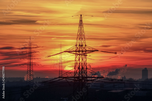 Strommasten und Industrie vor roter Sonne