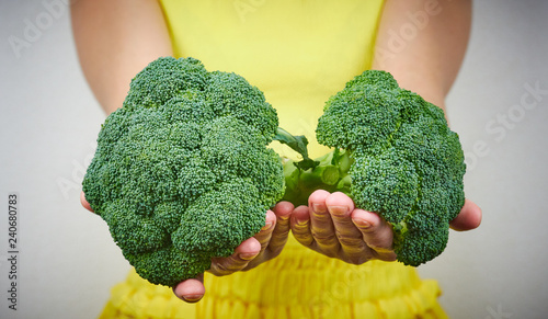 The concept of raw food. Woman holding a bunch of green, raw broccoli. a pair of green cabbage close-up. eating raw food. healthy food.