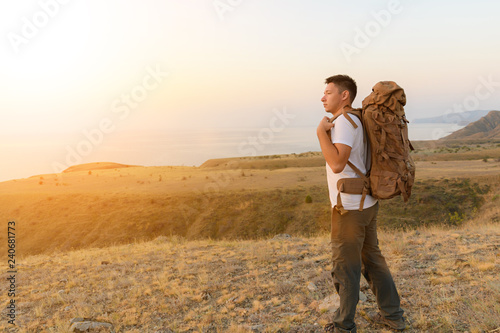 Tourist puts on his backpack in the middle of the steppe © haoka