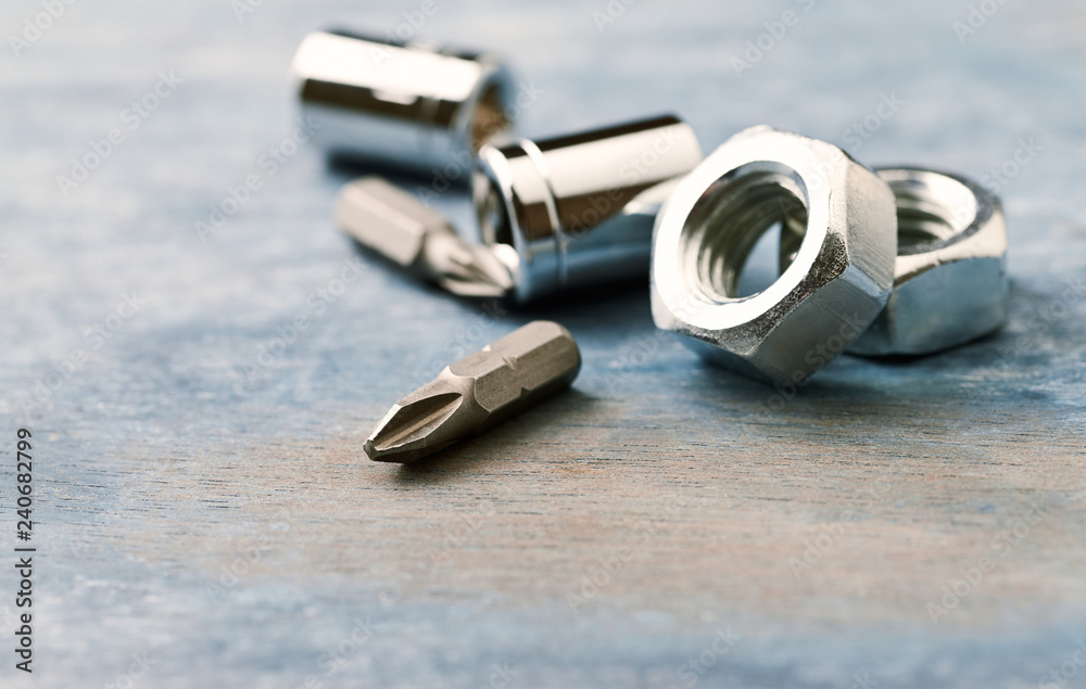 Bits for a screwdriver and hex nuts on wooden background. Close up. Copy space. Bits for a screwdriver and hex nuts on wooden background. Close up. Copy space.