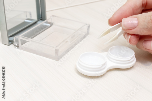 Cropped female hands taking contact lenses out of a container