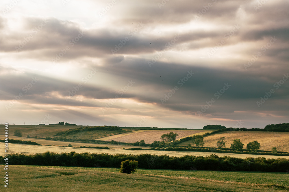 Obraz premium Sun Rays Through Clouds Over Countryside Fields