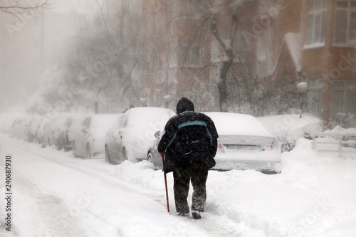 Old man trying to go to work on a snowy day