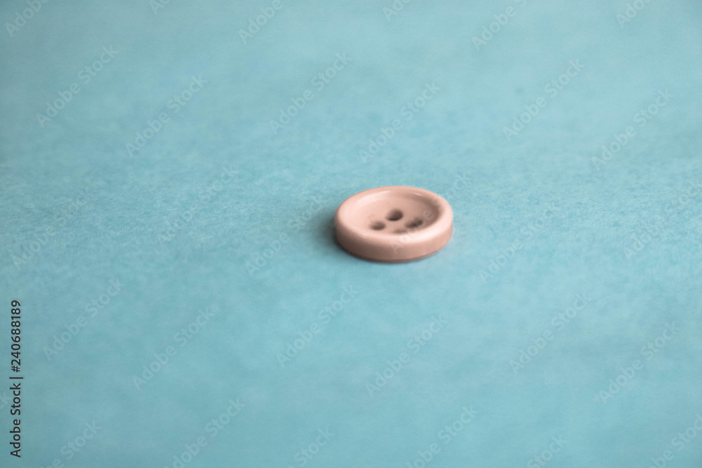 Beautiful texture with a round white button for sewing, needlework. Copy space. Flat lay. Blue background Beautiful texture with a round white button for sewing, needlework. Copy space. Flat lay. Blue background