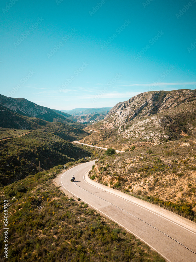 aerial mountains road panorama. Breathtaking curves perfect for motorcyclists or a car trip. On one side an asphalt road and on the other a dirt road, offroad.