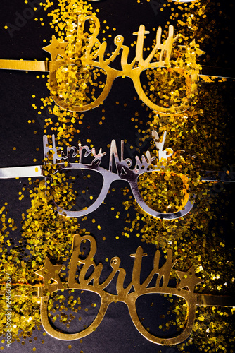 New Years Eve celebration background , 2019 number made with golden glitter candles and decorations, flatlay over a black board, luxury holiday concept, with funny party glasses.