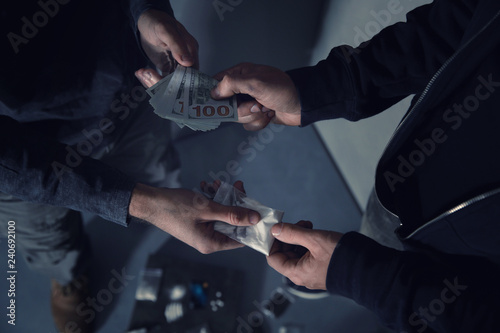 Addicted man buying drugs from dealer on blurred background, closeup