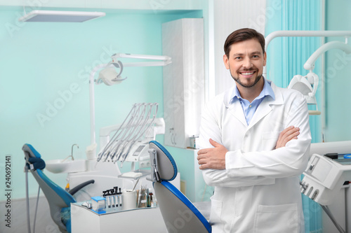Professional male dentist in white coat at workplace. Space for text photo
