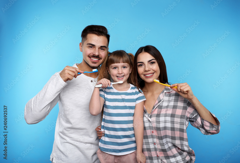 Little girl and her parents brushing teeth together on color background Little girl and her parents brushing teeth together on color background