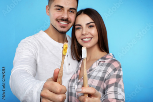 Happy couple with toothbrushes on color background. Teeth care