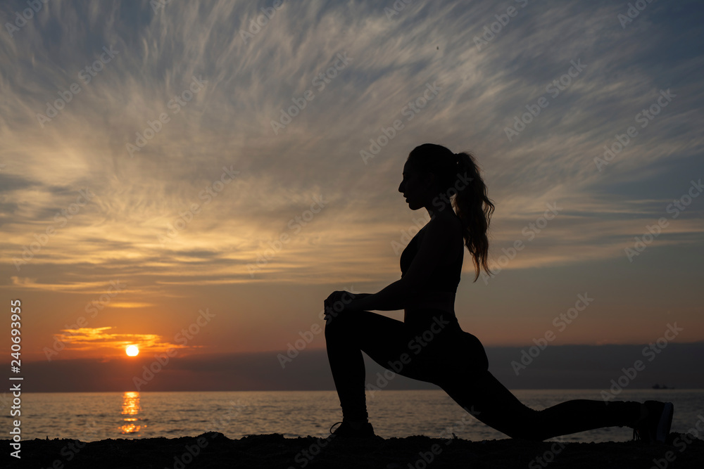 young woman does exercise at sunrise