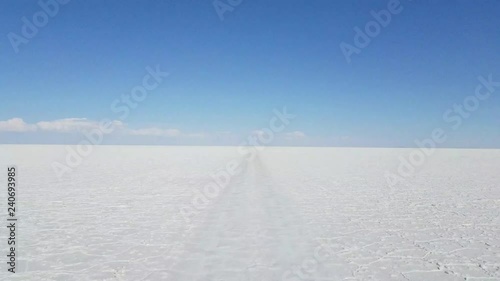 Driving through The Uyuni Salar in Bolivia. White salt flats and a bright blue sky. South a=America
