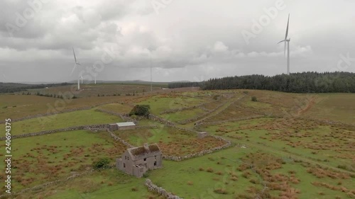 An aerial view of  wind turbines and an abandoned farm house between the towns of Spiddal and Moycullen in County Galway, Ireland photo