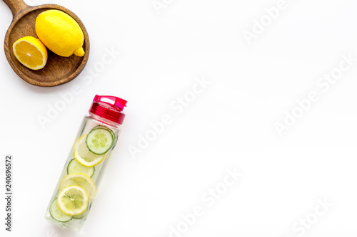 Detox infused water with slices of lemon and cucumber in bottle on white background top view space for text