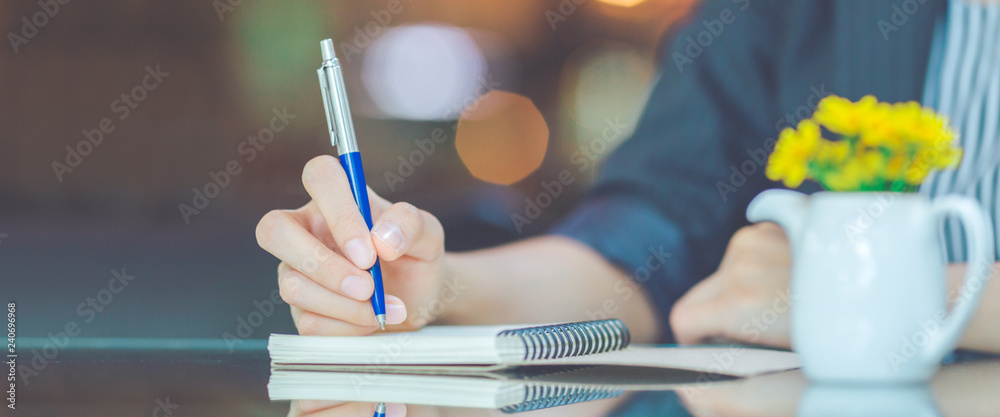 Business woman writing on a notebook.with a pen in the office.Web banner.
