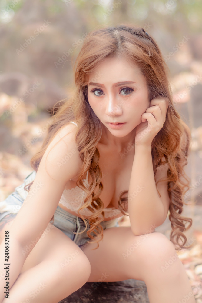 Asian Sexy women in jeans,posing at nature in the wild,hair female sitting on rock outdoors. Asian Sexy women in jeans,posing at nature in the wild,hair female sitting on rock outdoors.