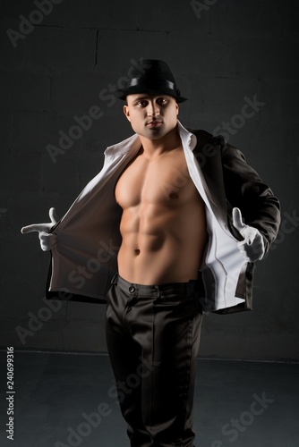 Young muscular man in a hat and unbuttoned shirt