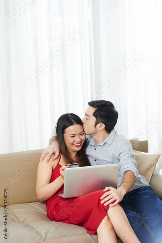 Young mixed-race couple in love shopping online for Valentine s Day presents and kissing