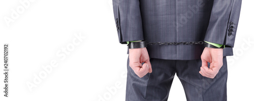 Handcuffs on a businessman hands behind his back isolated on a white background with copy space.