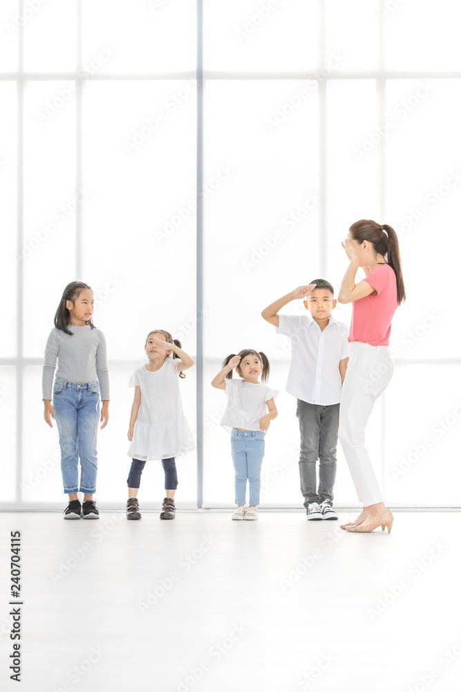Naklejka premium Asian kids salute to Asian woman in pink shirt, she salute backto them, they stand in front of big white window.