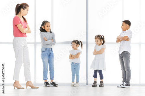 Asian woman in pink shirt and Asian boy and girls cross their one's arm, they stand in front of big white window.