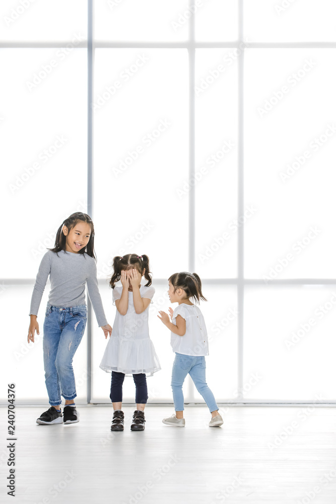 Asian kids point at Asian girl, the stand beside big white window. Asian kids point at Asian girl, the stand beside big white window.