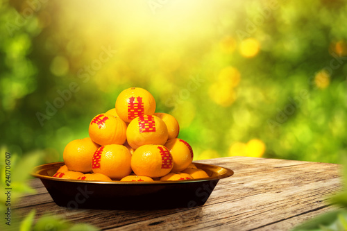 fresh orange fruits with red paper on wooden table top design with blur orange garden background