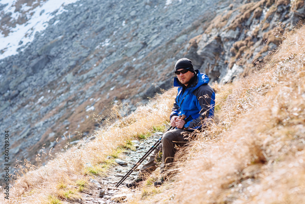 The man goes to the mountain with sticks for trekking in a wonderful autumn time