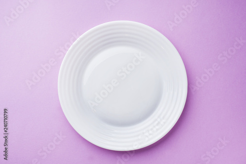 Empty white plate on pink background close up.