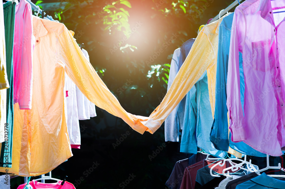 Colorful wet clothes hanging on the steel clothesline for drying by the ...