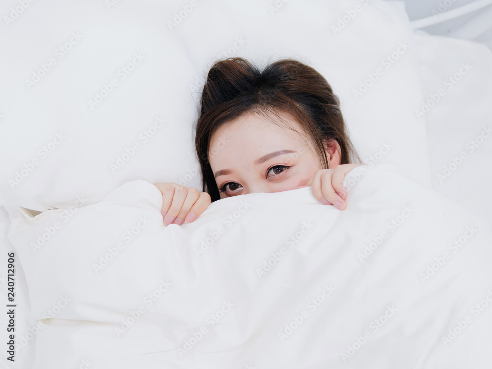 Funny smiling Chinese girl covering half of face with white blanket, young happy woman hiding and peeking from duvet, feels sweet, wide awake, head shot close up, top view. Funny smiling Chinese girl covering half of face with white blanket, young happy woman hiding and peeking from duvet, feels sweet, wide awake, head shot close up, top view.